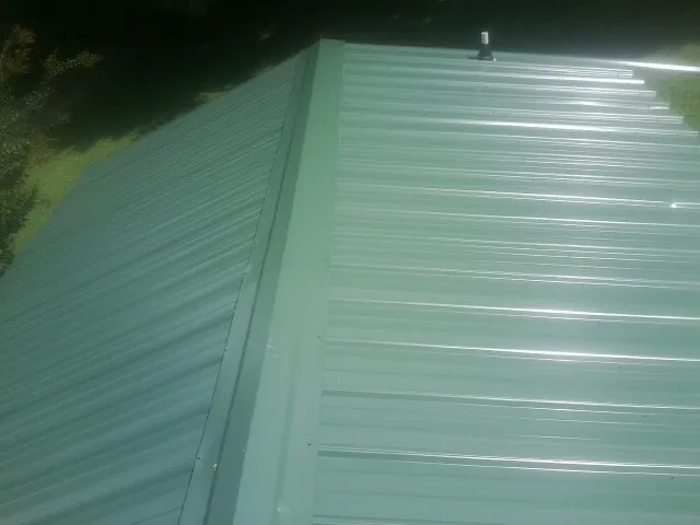 New green metal panels meeting at the ridge of a roof — Flat Roof Repair work by our crew in Berkeley Springs