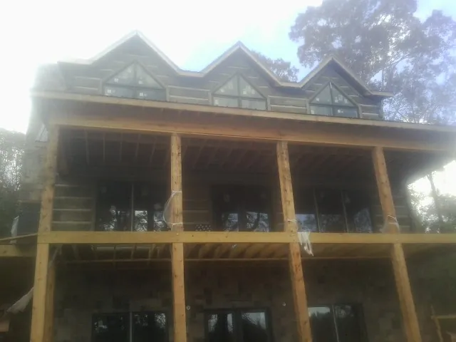 Dormers and porch framing on a large log home under construction — Roof Coating work by our crew in Berkeley Springs