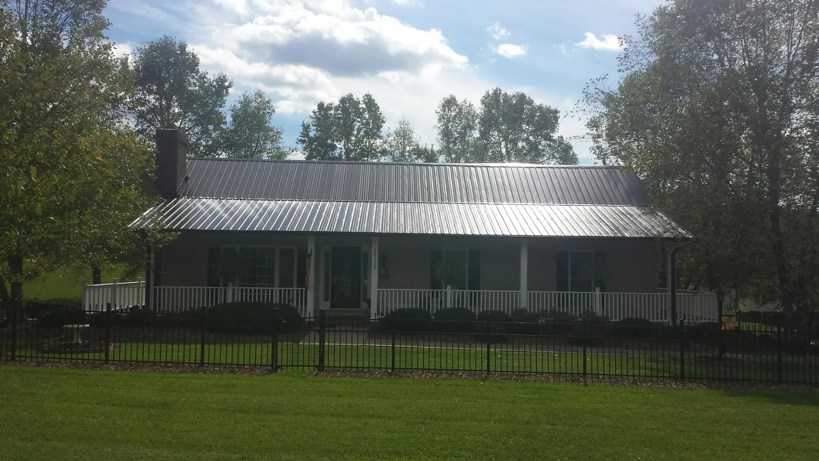 Gray metal roof on a brick ranch with a full width front porch — Gutter Guard Installation work by our crew in Berkeley Springs