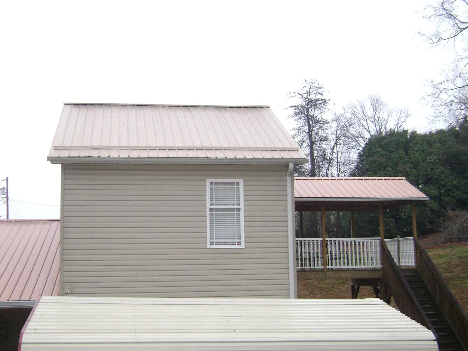 Tan metal roofs on a two story addition and attached porch, from a Roof Replacement job in Berkeley Springs