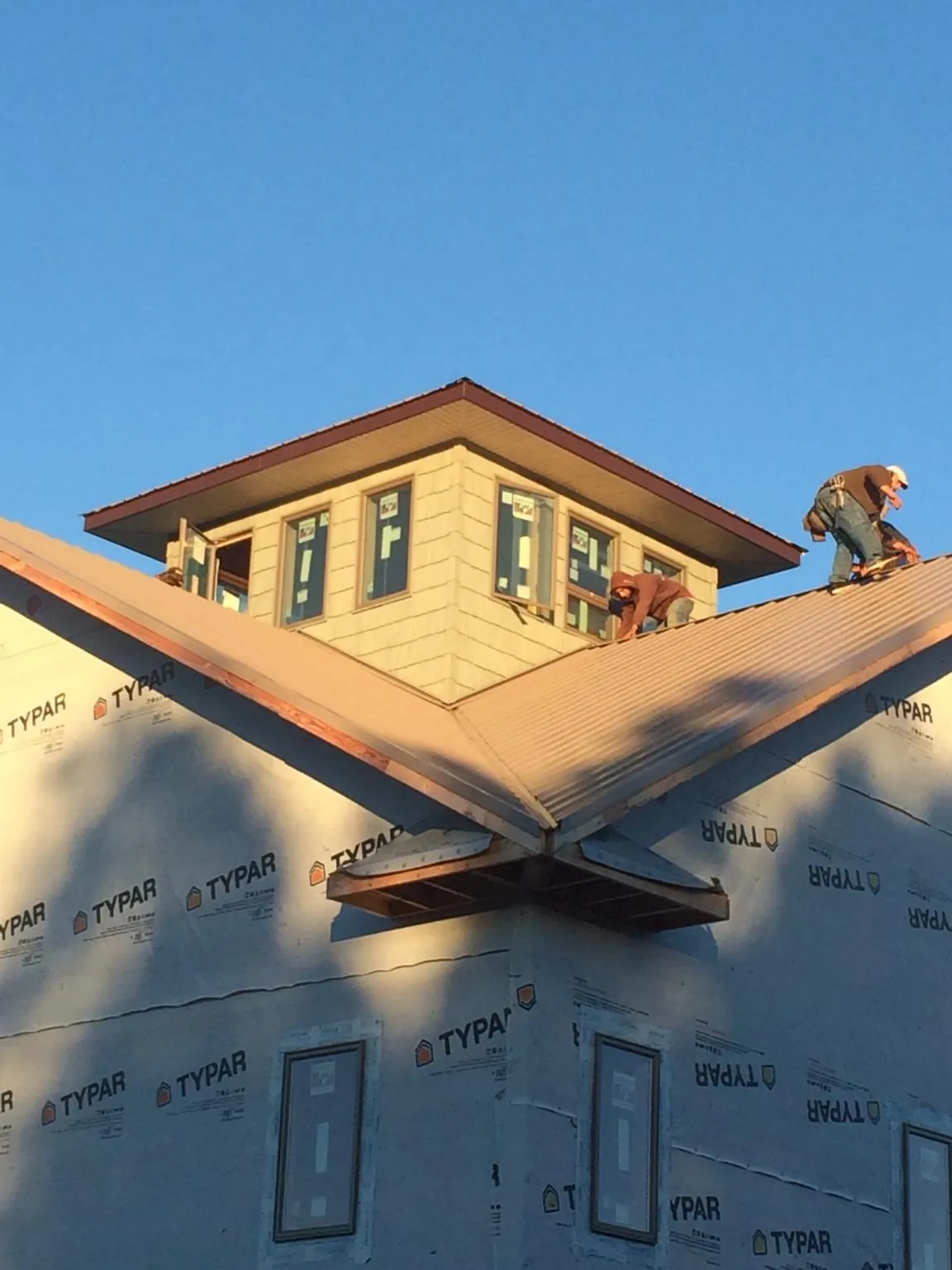 Roofers working around a rooftop cupola on a new metal roof at sunset — Roof Waterproofing in Berkeley Springs by Roofing Brothers